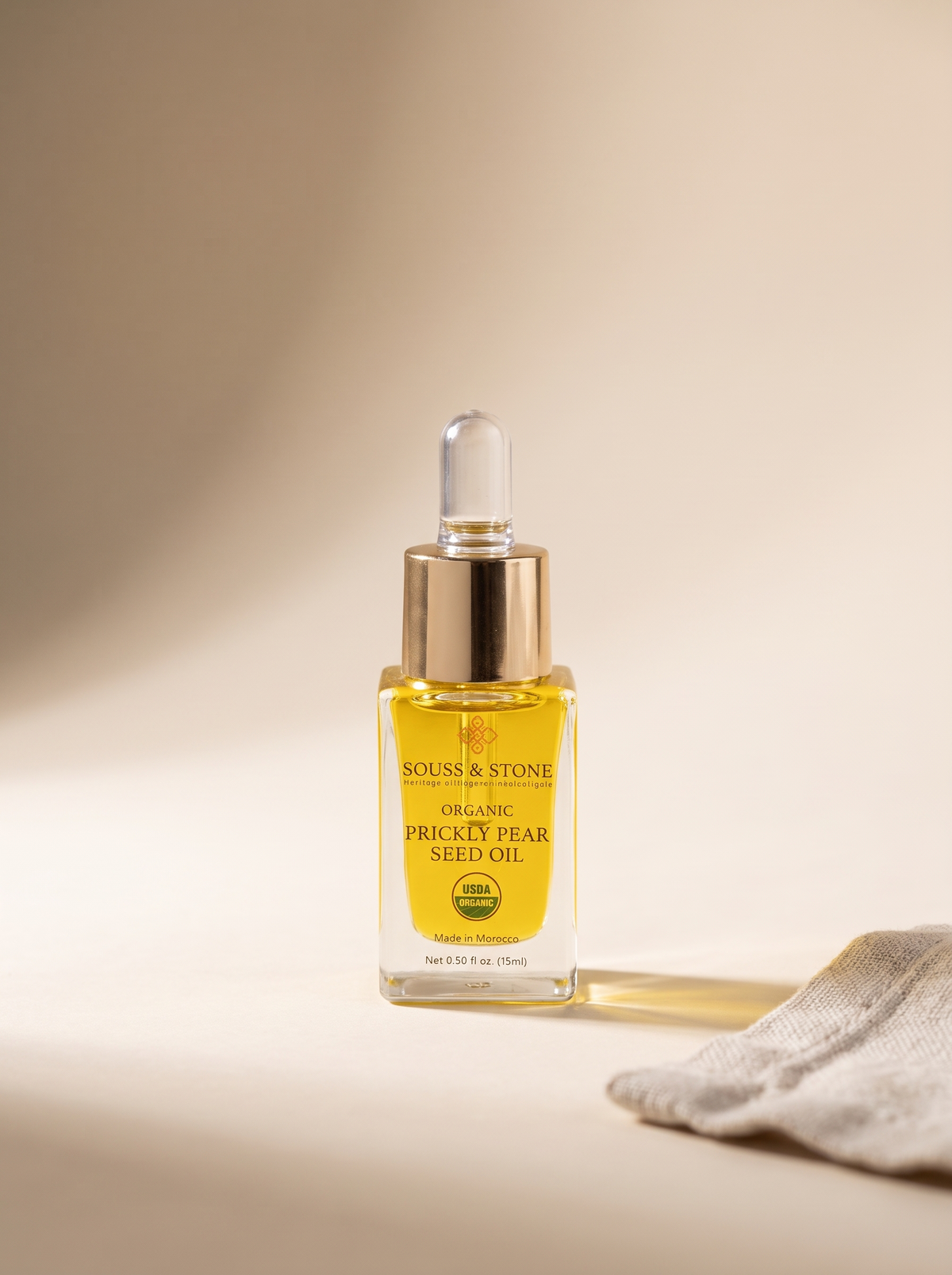 Bottle of Organic Prickly Pear Seed Oil, 15 ml, on a neutral sand background with linen