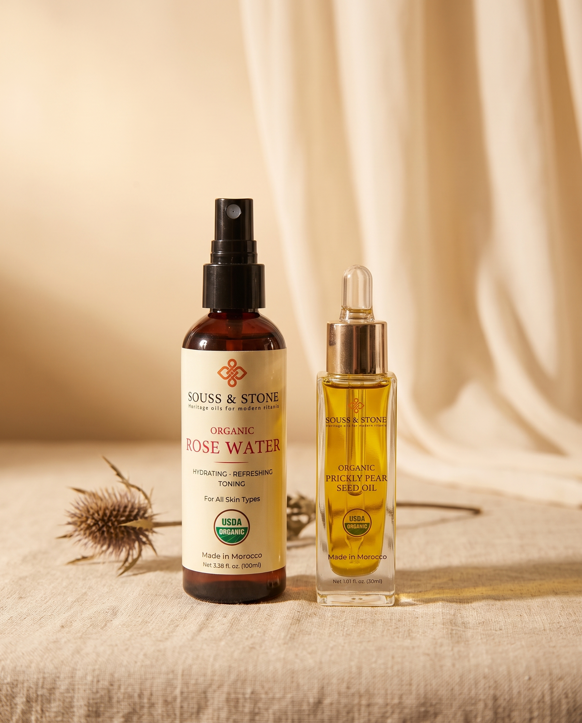 Organic Moroccan Rose Water and Organic Prickly Pear Seed Oil bottles standing together on linen